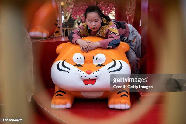 Children play on sculptures of cartoon tigers in a shopping mall on January 20, 2022 in Wuhan, Hubei Province, China. Life for many of the residents...