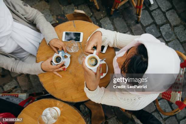 deux amies assises dans un bar en train de déguster un café chaud - bar paris photos et images de collection