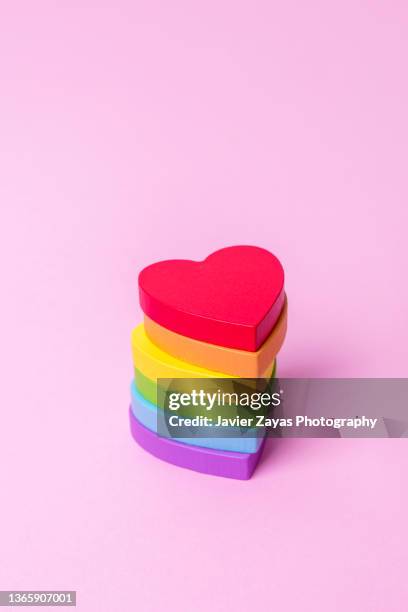 heart shaped wooden rainbow flag colored pieces over pink background - regenbogenfahne stock-fotos und bilder