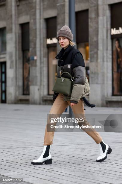 Influencer Lisa Hahnbueck wearing a black, brown and olive green striped winter jacket by Moncler, a black cashmere turtleneck pullover by Dorothee...