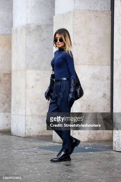 Influencer Gitta Banko wearing a blue turtleneck pullover by Intimissimi, blue pants by Nili Lotan, a black belt by Celine, black long leather gloves...