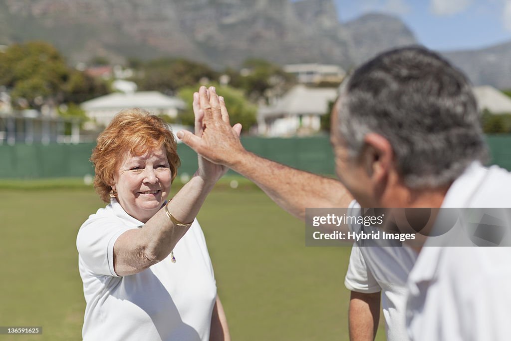 Older couple high fiving outdoors