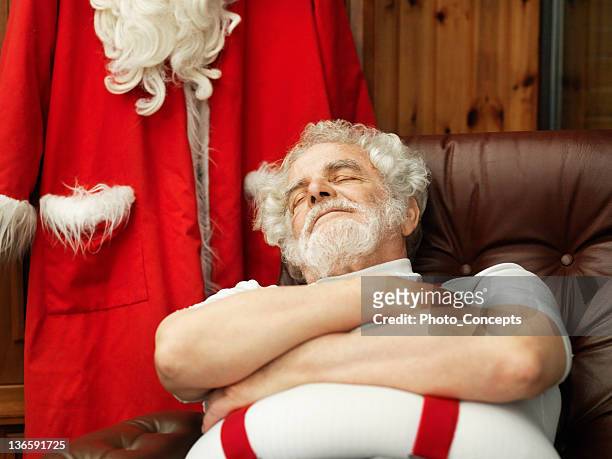 man with santa claus suit napping - santa claus lying stock pictures, royalty-free photos & images