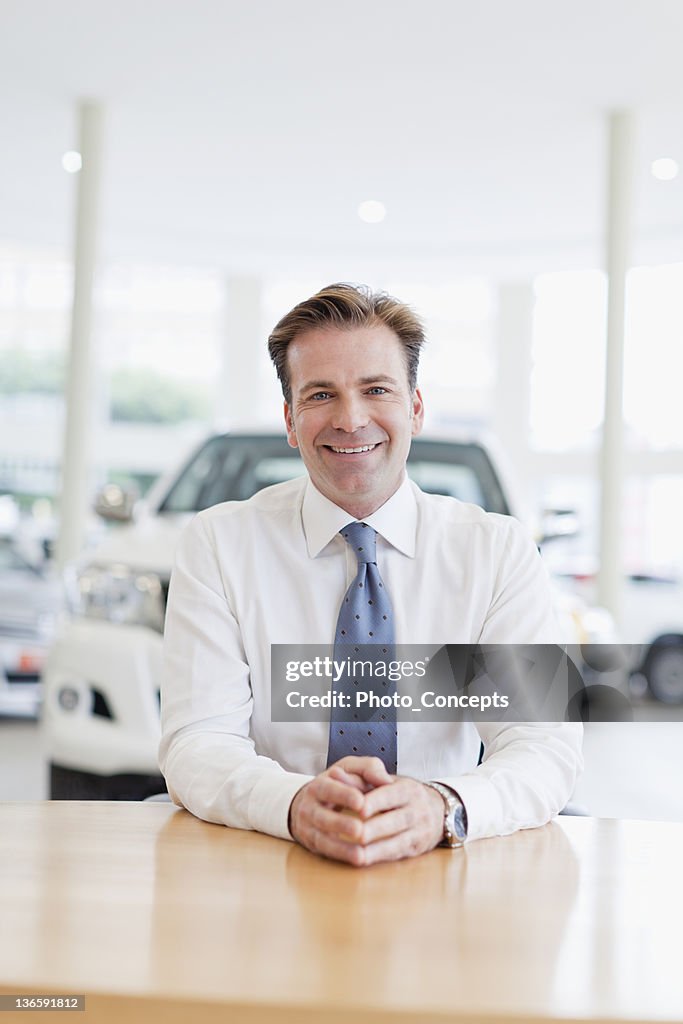 Car salesman smiling at desk