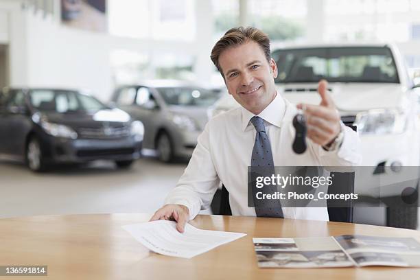 car salesman handing keys over desk - bilförsäljare bildbanksfoton och bilder