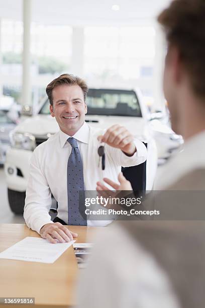 car salesman handing keys to customer - car salesman stock pictures, royalty-free photos & images