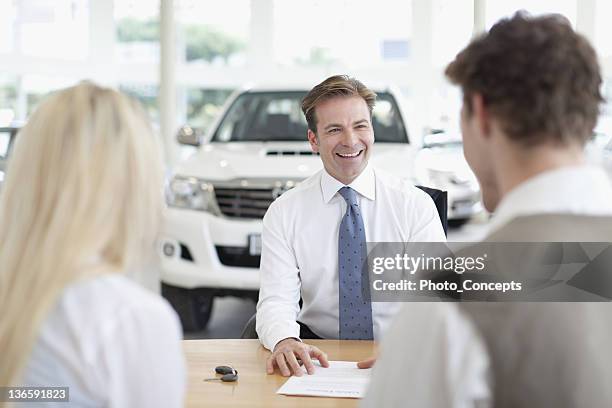 car salesman with customers at desk - skjorta och slips bildbanksfoton och bilder