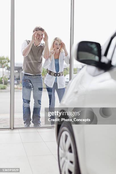 couple peering in car dealership - new car stock pictures, royalty-free photos & images