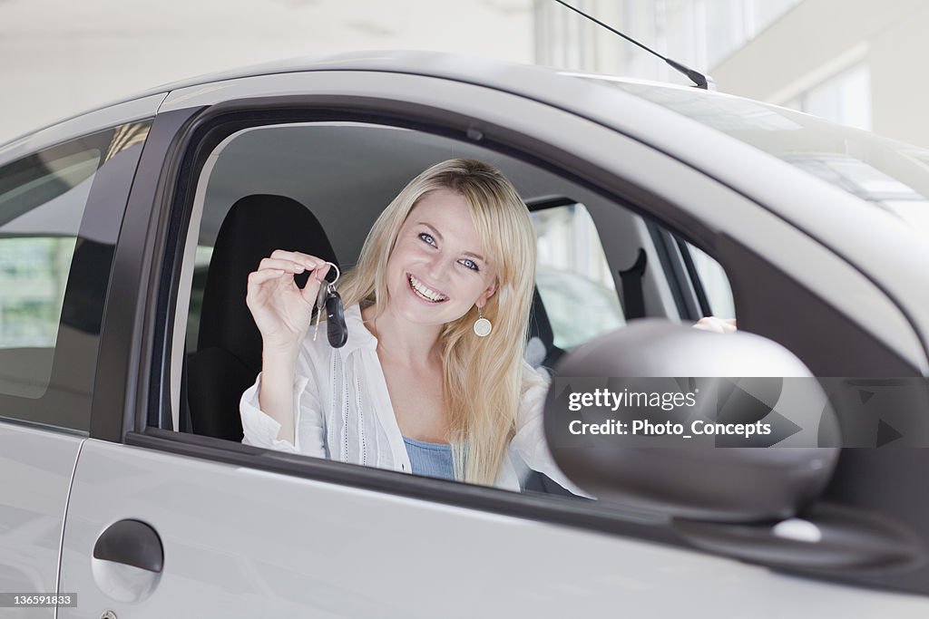 Smiling woman holding keys to new car