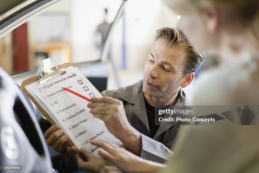 Mechanic showing checklist to customer