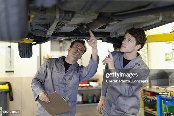 mechanics examining underside of car - will jacks stock pictures, royalty-free photos & images