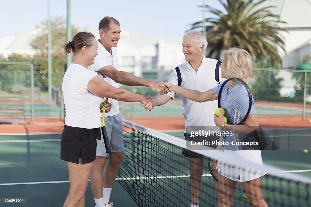 Older couples shaking hands at tennis