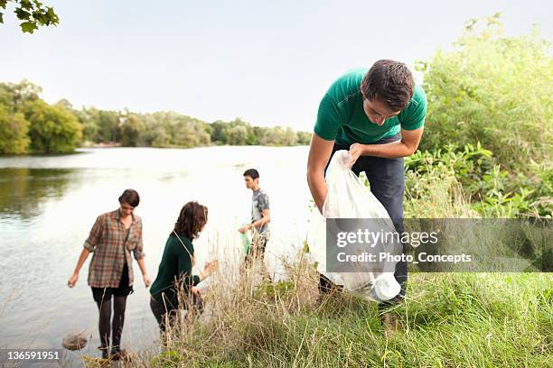 people picking up garbage in park - garbage bag stock pictures, royalty-free photos & images