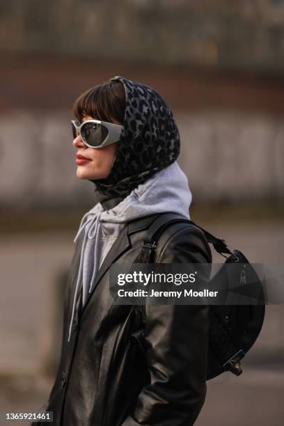 Lea Naumann wearing black vintage Dior leather bag, grey Dior scarf, grey Cartier x Highsnobiety hoodie, grey Balenciaga shades, and black vintage...