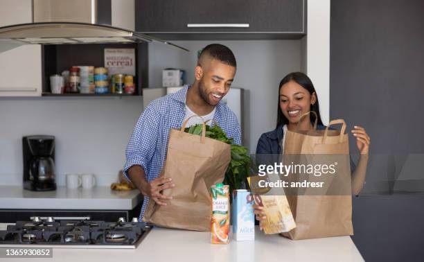 young couple unpacking the groceries at home - grocery delivery stock pictures, royalty-free photos & images