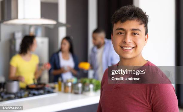 happy young man smiling at home with a group of roommates at the background - civilian stock pictures, royalty-free photos & images