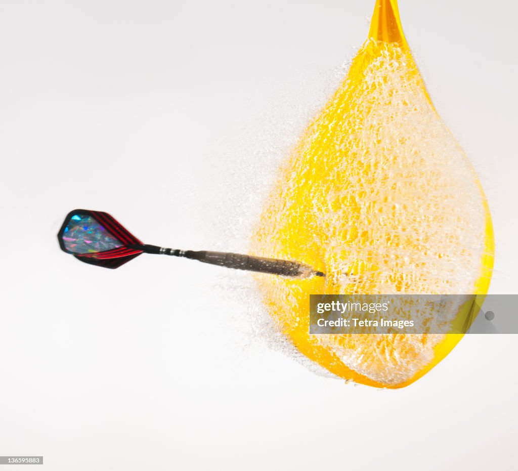 Studio shot of dart puncturing water-filled balloon