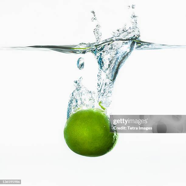 studio shot of green apple falling into water - apple water splashing stock-fotos und bilder