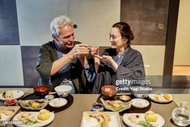 hispanic couple toasts with sake at a machiya hotel in kyoto. - 天ぷら ストックフォトと画像