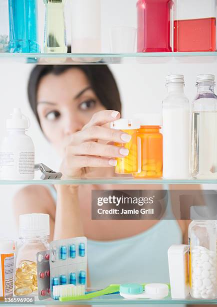 usa, new jersey, jersey city, woman taking medicine from cabinet - medicine cabinet stock pictures, royalty-free photos & images