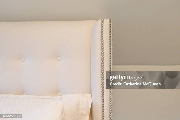 upholstered linen headboard with nailhead studded trim - upholstry stockfoto's en -beelden