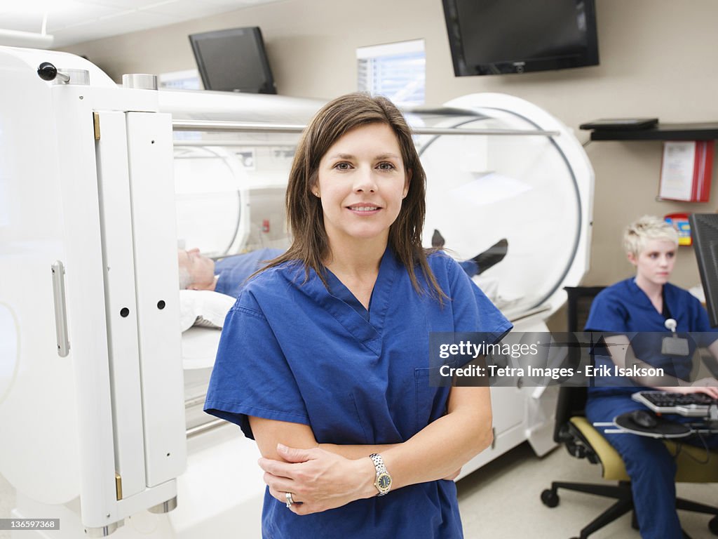 USA, Utah, Ogden, Young female nurse standing in front of CAT scanner