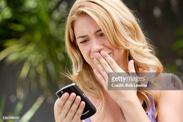 usa, california, los angeles, young woman text-messaging, with facial expression - offensive stockfoto's en -beelden