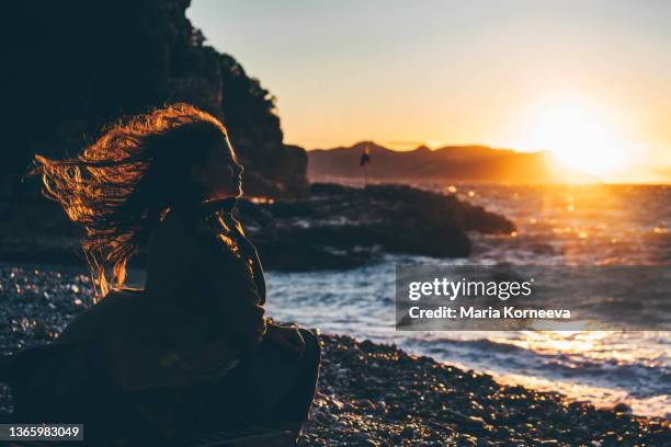 happy young woman traveler sitting against stunning view of stormy mediterranean sea - air crash investigation stock pictures, royalty-free photos & images