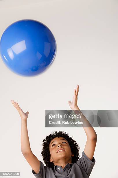 studio shot of boy (8-9) tossing blue ball - 8 ball stock-fotos und bilder