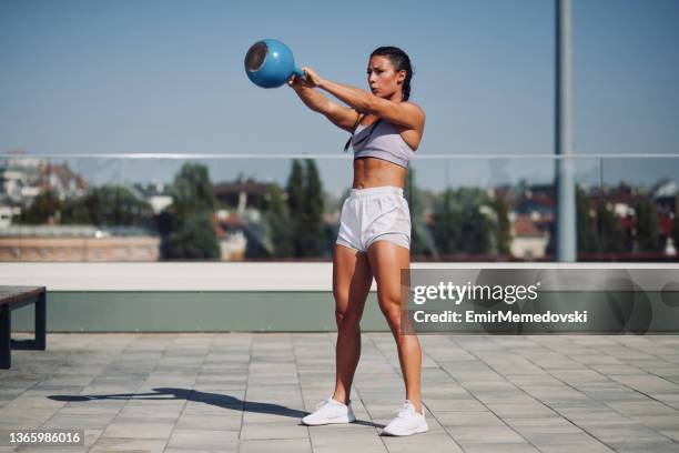 mujer joven haciendo ejercicio con pesas de campana de kettle al aire libre - kettlebell swing fotografías e imágenes de stock