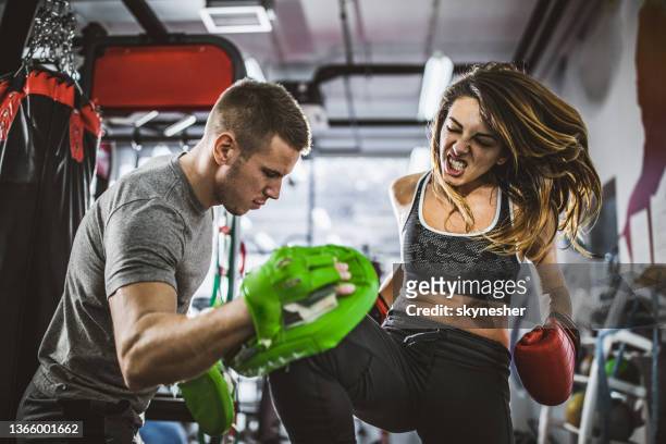 tough woman having kick boxing training with a coach. - self defense stock pictures, royalty-free photos & images