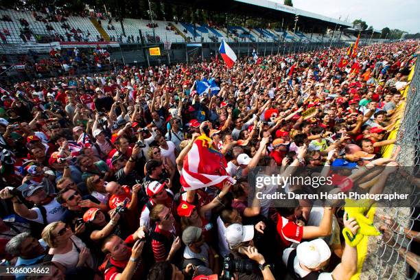 Thousands of men, women and children, Scuderia Ferrari Formula One team fans known as Tifosi, and Formula One fans, in a crowd of people waving their...