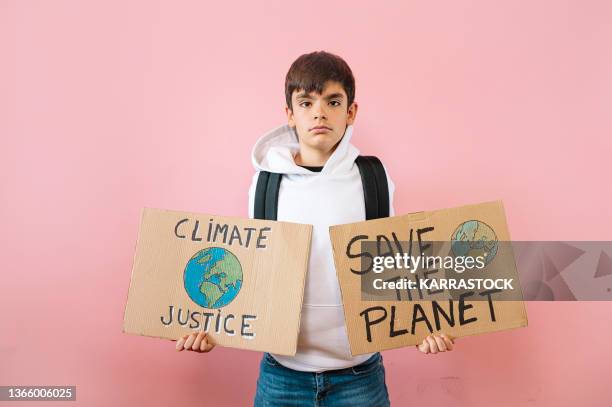 young teenage holding two cardboard signs that says save the planet and climate justice. - exigir fotografías e imágenes de stock