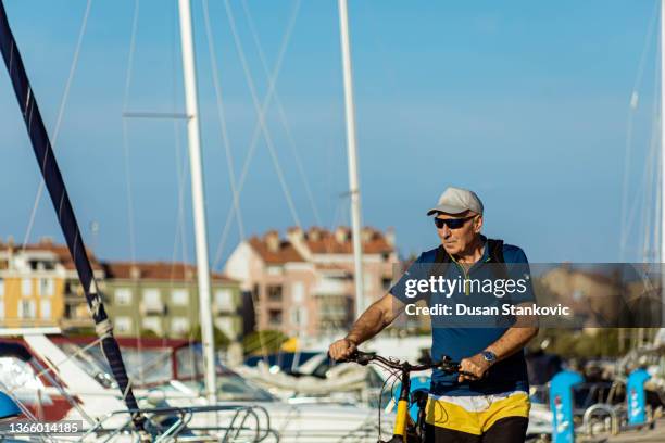 caucaisan senior men, pushing his bike, at the marina - förtöjd bildbanksfoton och bilder