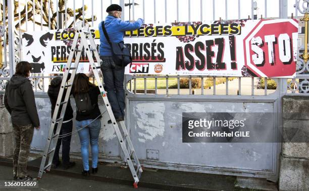 Installation d'une banderole sur des grilles "Ecoles, collèges, lycées, personnes méprisées, assez ! STOP" lors de la grève et manifestation dans...