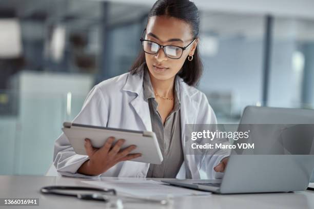 shot of a young female doctor using a digital tablet at work - jaleco imagens e fotografias de stock