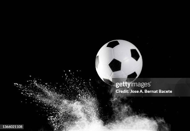 impact and rebound of a soccer ball on a surface of earth and gunpowder on a black background - ballon rebond stock-fotos und bilder