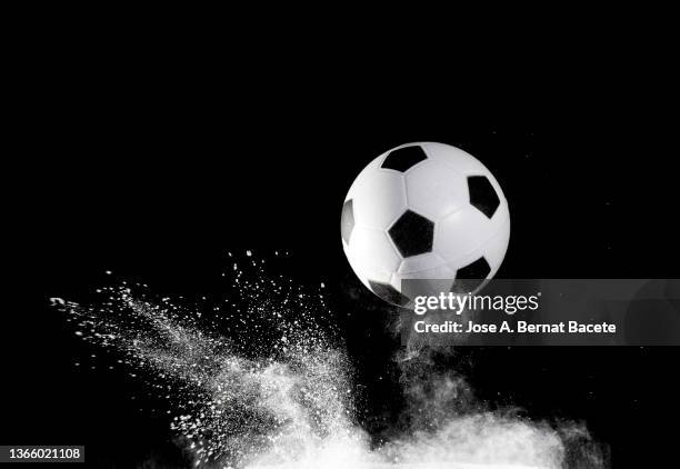 impact and rebound of a soccer ball on a surface of earth and gunpowder on a black background - ballon de football - fotografias e filmes do acervo