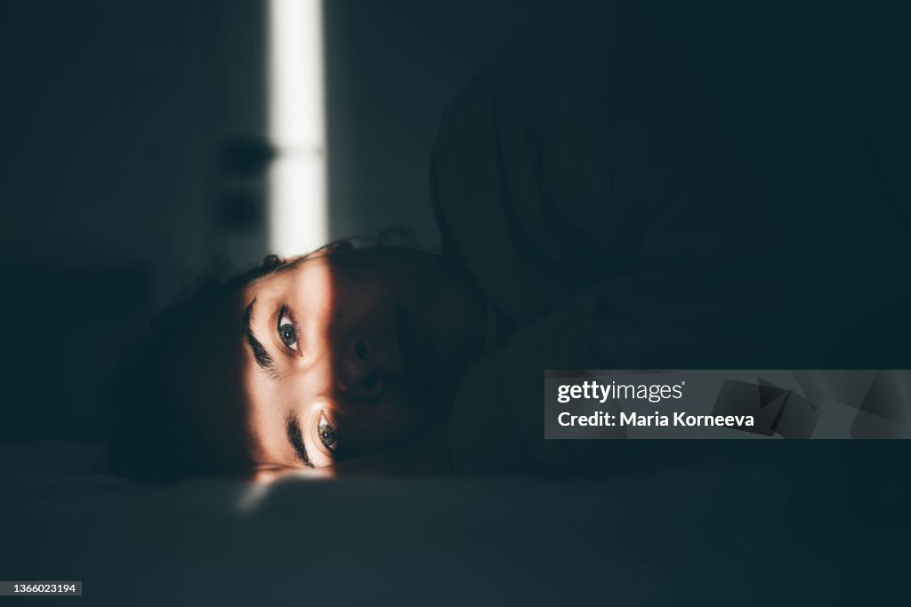 Worried young woman lying on bed at home.