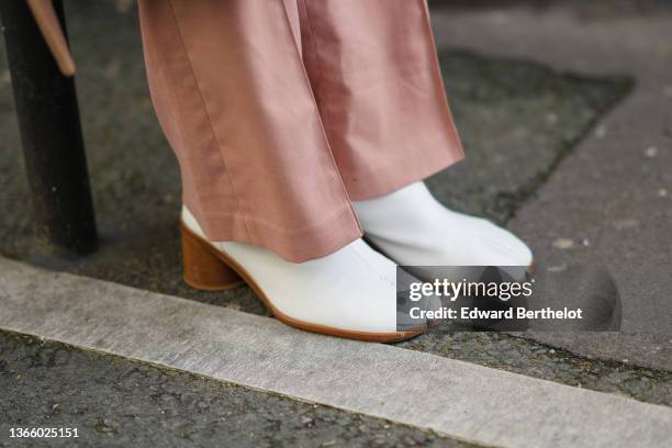 Guest wears pale pink wide legs / flares denim jeans pants, white shiny leather slit / split toe cap / block heels ankle boots, outside Louis...