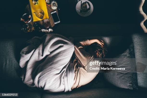 worried young woman lying on sofa at home. - schmerz stock-fotos und bilder