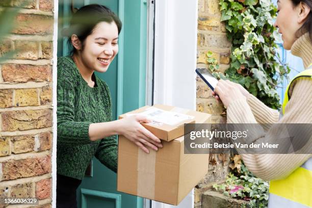 courier photographs parcels delivered to door, held by recipient. - home delivery fotografías e imágenes de stock