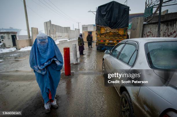 An Afghan woman begs at a wintry Taliban checkpoint on the Kabul road south to Pul-e Alam, Afghanistan, on January 17, 2022. The UN World Food...