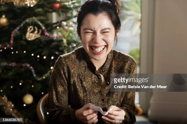 woman is laughing, when reading  joke at christmas dinner. - 聖誕拉炮 個照片及圖片檔