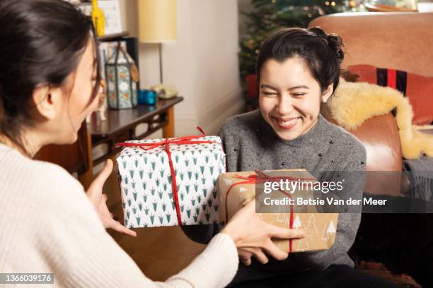 friends are exchanging presents in living room. - christmas gift exchange stock pictures, royalty-free photos & images