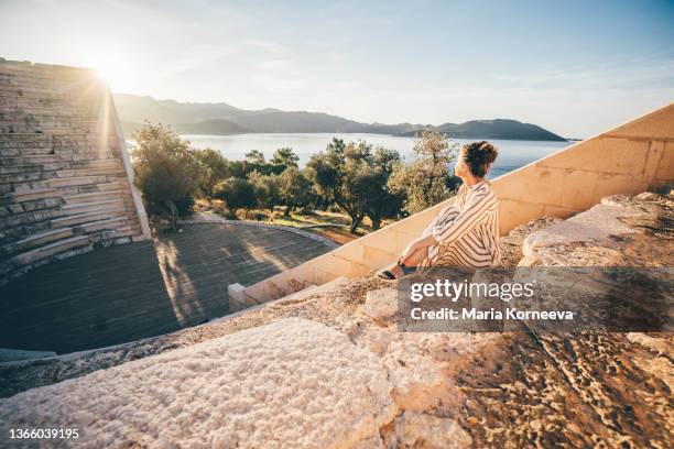 young woman traveler sitting on step of ancient amphitheater - antalya province stock pictures, royalty-free photos & images