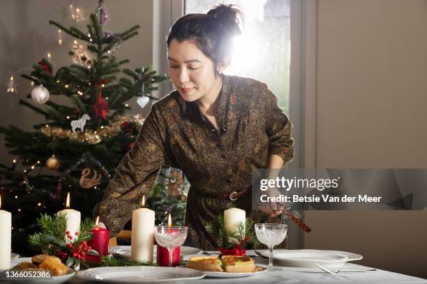 woman sets table in preparation for christmas dinner. - candle sets stockfoto's en -beelden