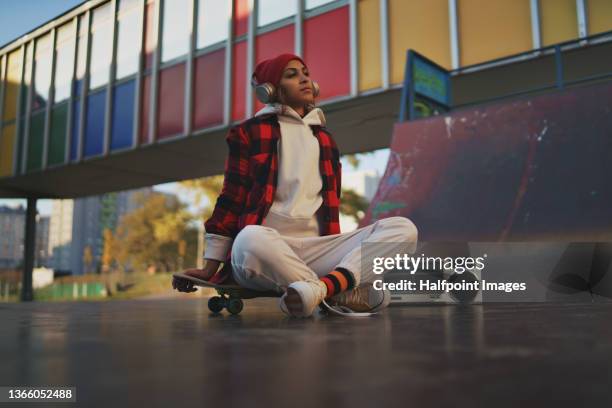 low angle view of young woman outdoors in the city, with skateboard. - sport for life stock pictures, royalty-free photos & images