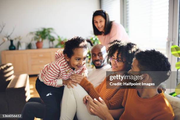 happy multiracial family with three children sitting on sofa together at home. - mixed race person foto e immagini stock