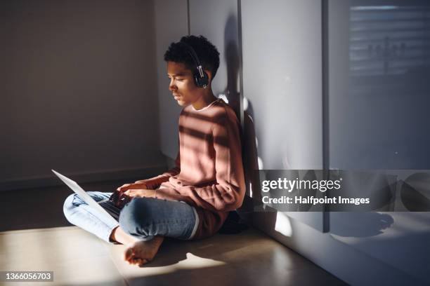 addicted teenage boy sitting on floor using laptop and headphones in evening at home. - teenage boys stock photos et images de collection